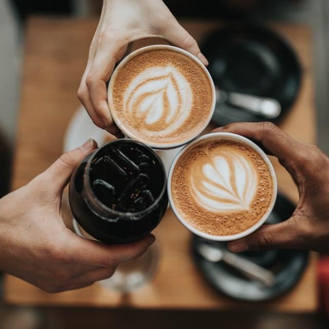 Friends toasting with latte art coffees